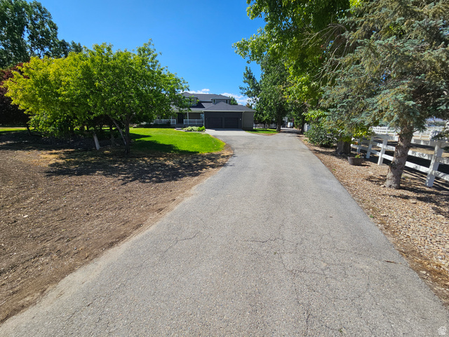 812 East Bates Cyn Road Tooele, UT 84074 - Photo 3 of 144 Paved driveway leading to a residence featuring a dark-toned facade, white porch columns, and a multi-car garage