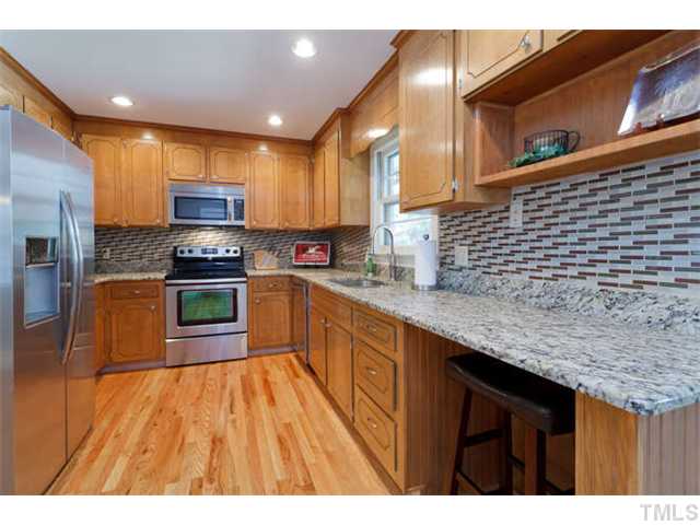 1605 Su John Road Raleigh, NC 27607 - Photo 7 of 25 a kitchen with stainless steel appliances kitchen island granite countertop a sink a stove top oven a counter space and cabinets