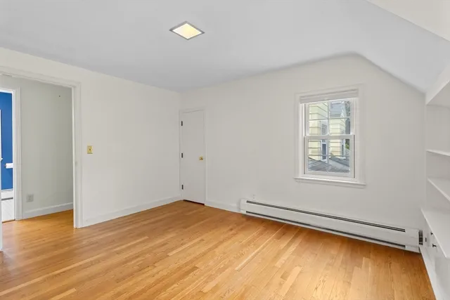 an empty room with wooden floor closet and windows
