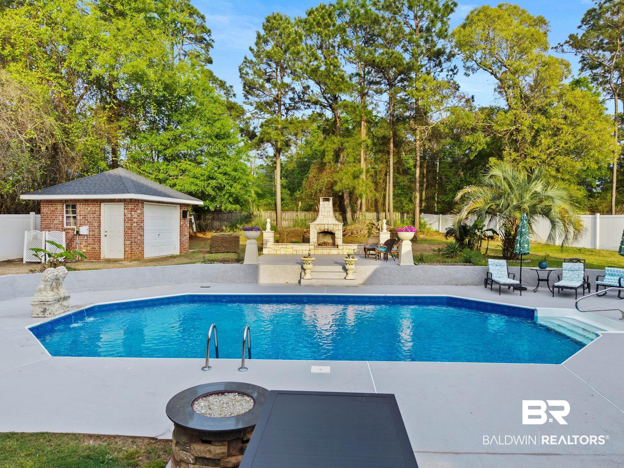 2 Speckle Trout Route Daphne, AL 36527 - Photo 49 of 61 View of pool with exterior fireplace, patio surround, a fenced backyard, and an outbuilding