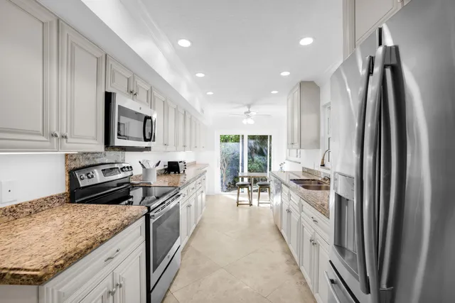 a kitchen with stainless steel appliances granite countertop a refrigerator a stove and a sink