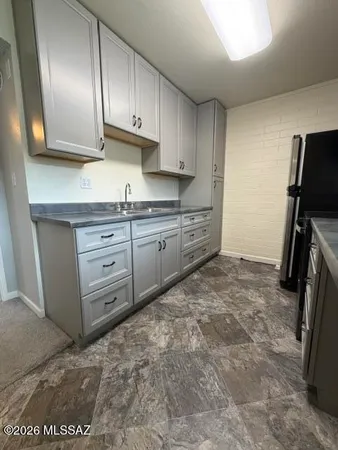 view of kitchen with granite countertop cabinets and refrigerator
