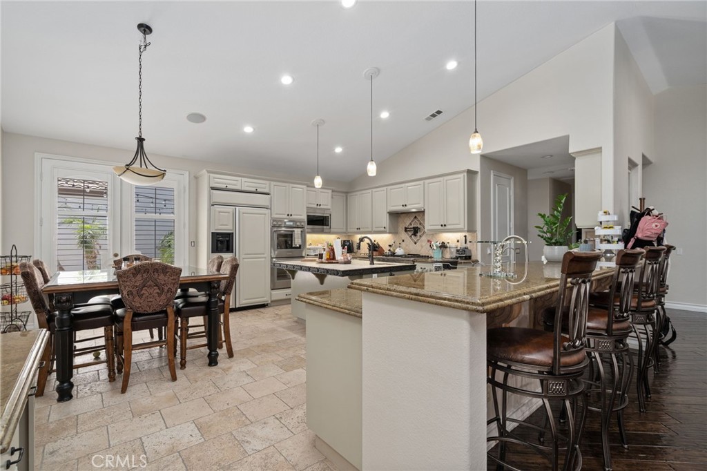 2885 Citrocado Ranch Street Corona, CA 92881 - Photo 19 of 51 a kitchen with kitchen island a dining table chairs and white cabinets