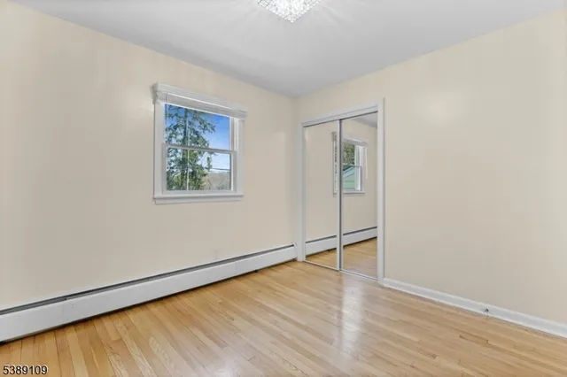 an empty room with wooden floor closet and windows