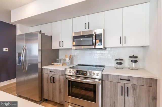 a kitchen with stainless steel appliances granite countertop white cabinets a refrigerator a stove a sink and white cabinets