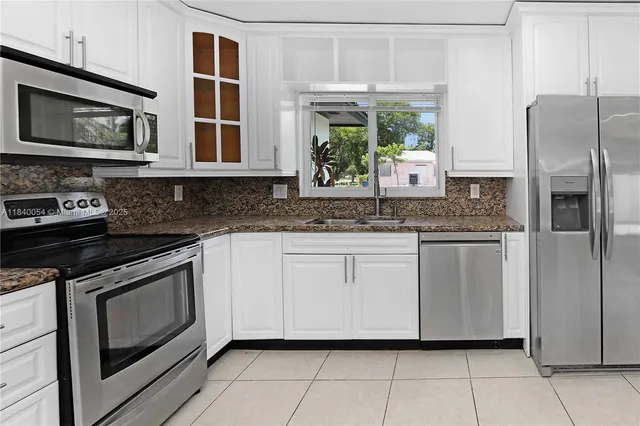 a kitchen with stainless steel appliances granite countertop a stove a sink and a microwave