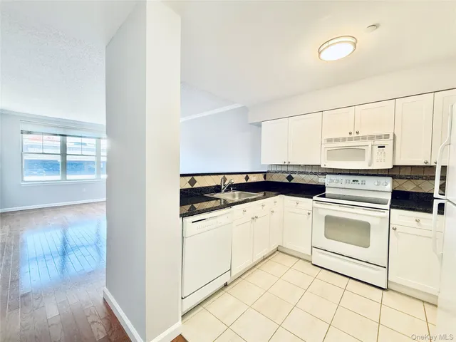 a kitchen with granite countertop white cabinets and a sink