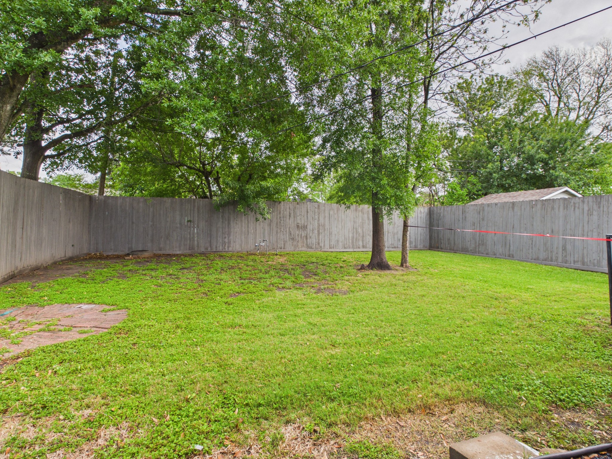 4927 Kelso Street Houston, TX 77021 - Photo 38 of 45 This photo shows a spacious backyard with a well-maintained lawn, several mature trees, and a tall wooden privacy fence. Ideal for outdoor activities and relaxation.