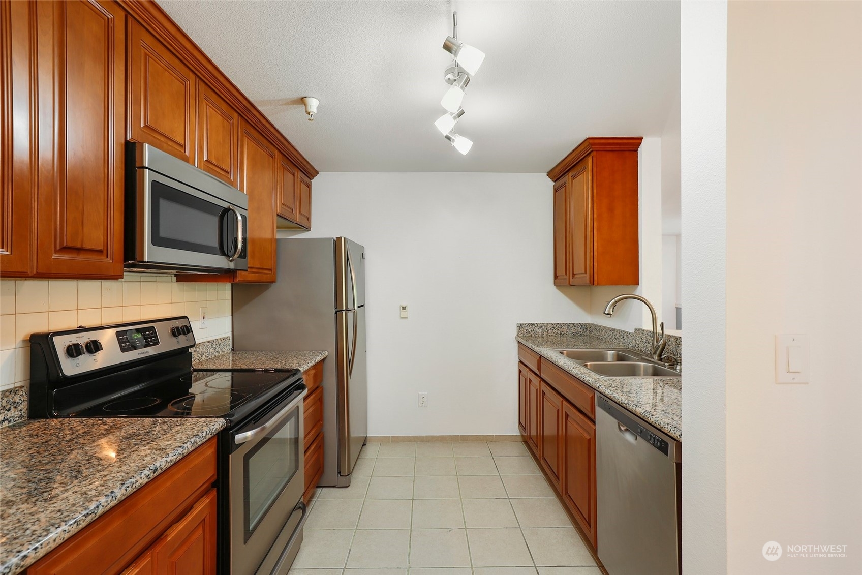 901 Sunset Boulevard Northeast, Unit D115 Renton, WA 98056 - Photo 3 of 19 a kitchen with stainless steel appliances granite countertop a sink stove microwave and refrigerator