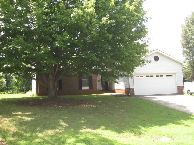a view of a house with a big yard and large tree