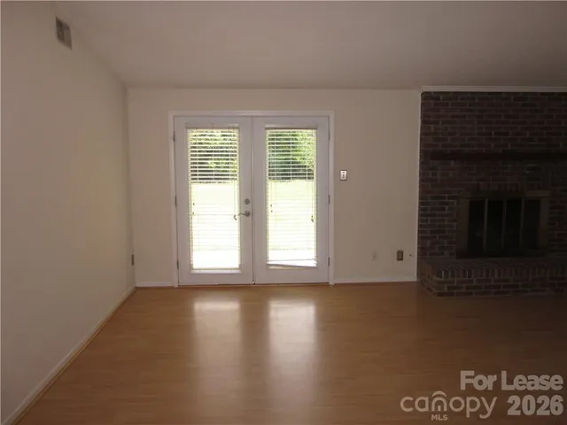 a view of an empty room with wooden floor and a fireplace