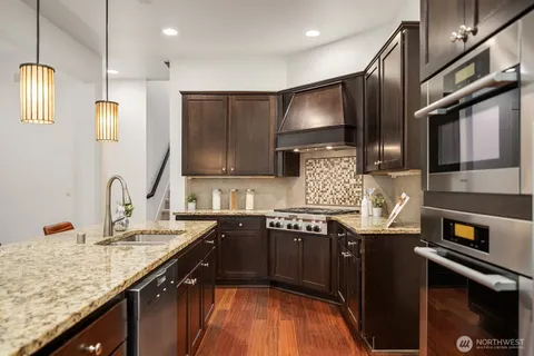 a kitchen with stainless steel appliances granite countertop a sink a stove and a wooden floors