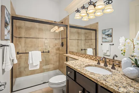 a bathroom with a granite countertop sink a toilet a mirror and shower