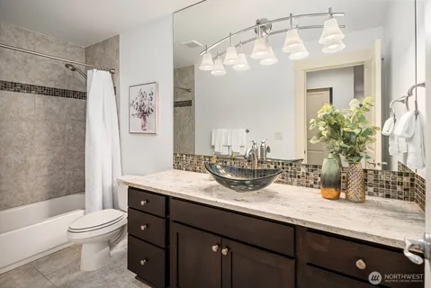 a bathroom with a granite countertop sink a toilet a mirror a vanity and shower