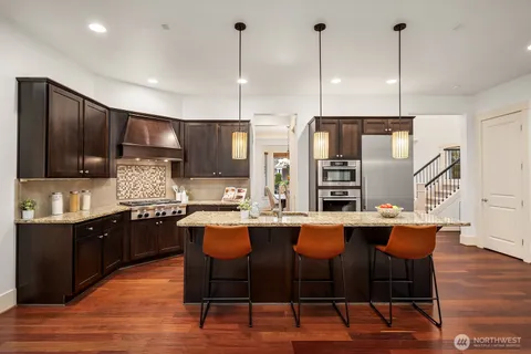 a kitchen with stainless steel appliances kitchen island granite countertop a table chairs stove and sink