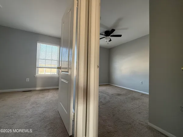 an empty room with windows and a ceiling fan