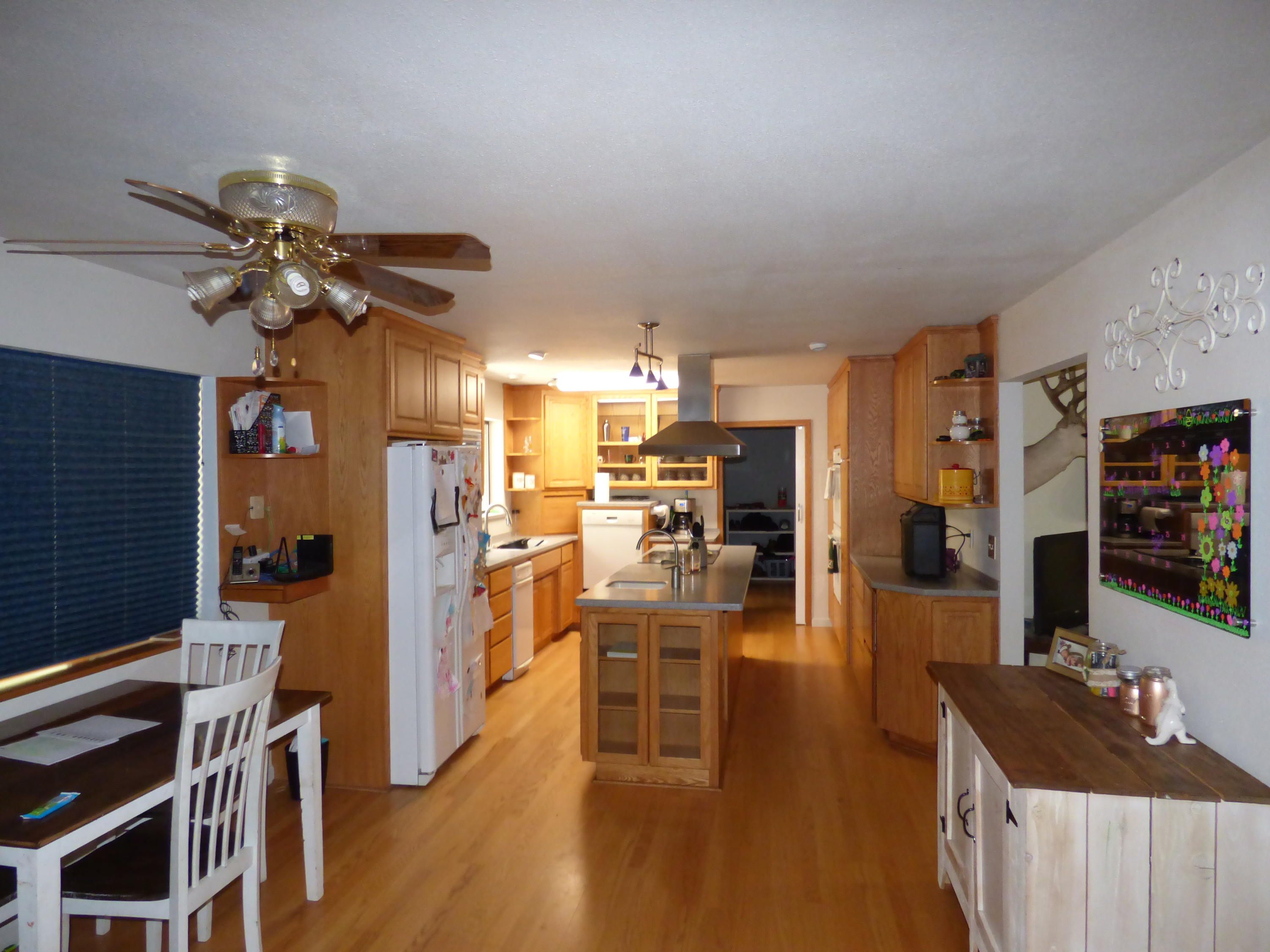 640-775 Iris Road McArthur, CA 96056 - Photo 7 of 8 a kitchen with stainless steel appliances kitchen island granite countertop a refrigerator a stove a sink a dining table and chairs with wooden floor