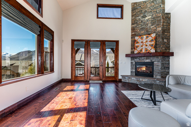 5326 North Oldgate Road Heber City, UT 84032 - Photo 3 of 32 Spacious room featuring vaulted ceilings, a prominent stone-clad fireplace with a substantial wood mantle, rich wood-finish flooring, and large windows with mountain scenery