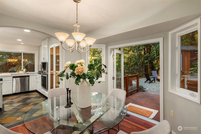 a dining room with wooden floor a chandelier a glass table and chairs