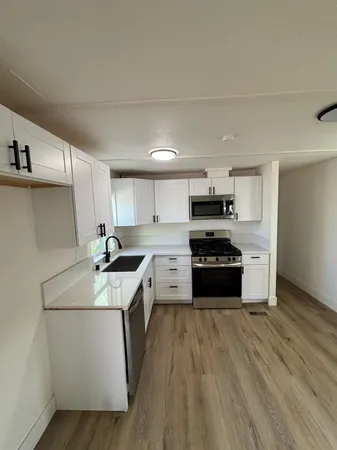 a kitchen with granite countertop a sink cabinets and stainless steel appliances