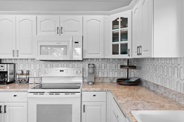 a kitchen with white cabinets and appliances