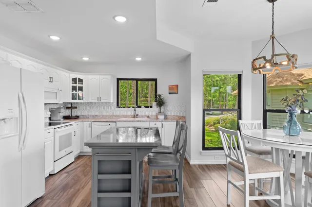 a kitchen with stainless steel appliances granite countertop a table chairs stove and refrigerator