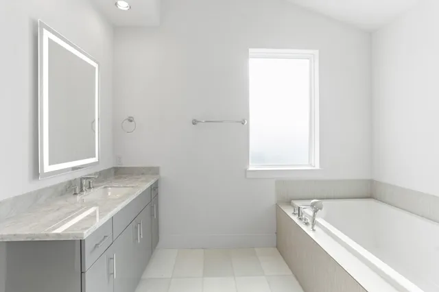 a bathroom with a granite countertop sink a bathtub and window