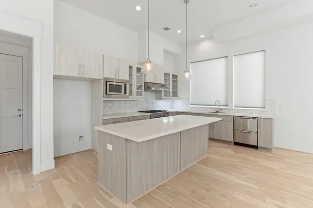 a large kitchen with stainless steel appliances a sink stove and cabinets