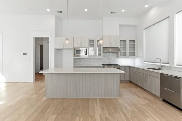 a large kitchen with stainless steel appliances kitchen island a large counter top and a wooden floors