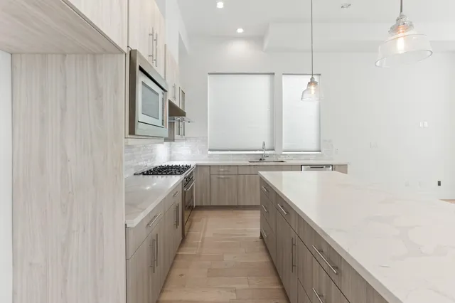 a kitchen with stainless steel appliances granite countertop a sink and dishwasher a stove top oven with wooden floor