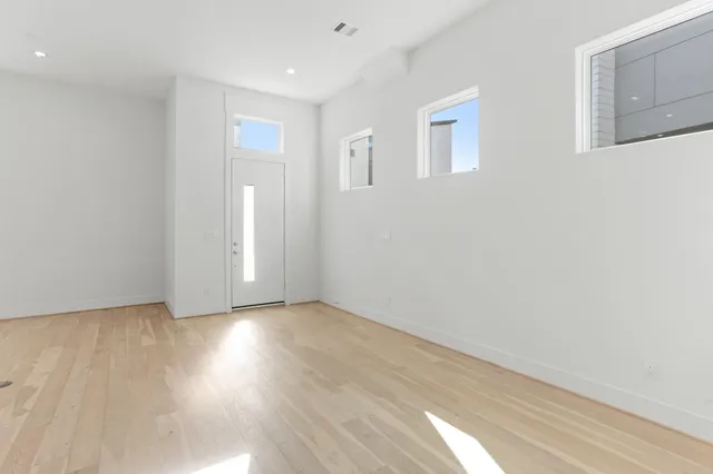 a view of an empty room with wooden floor and a window