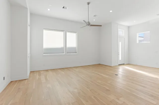 an empty room with wooden floor and windows