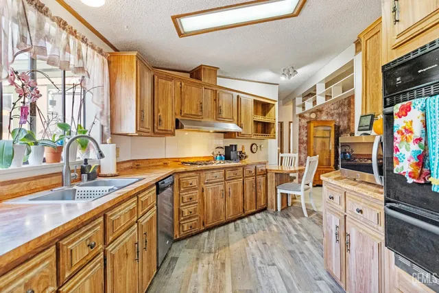 a kitchen with stainless steel appliances granite countertop a sink dishwasher stove and wooden cabinets
