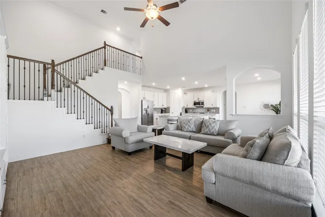 a living room with couches and kitchen view with wooden floor