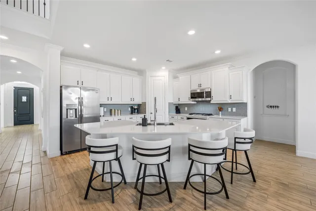 a kitchen with stainless steel appliances granite countertop a dining table chairs refrigerator sink and cabinets