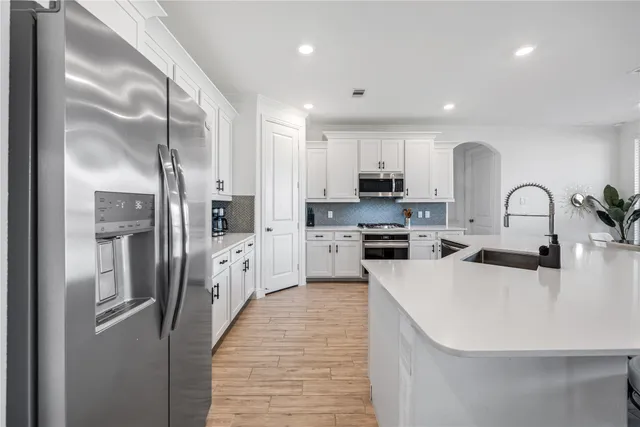 a kitchen with stainless steel appliances a refrigerator sink and white cabinets