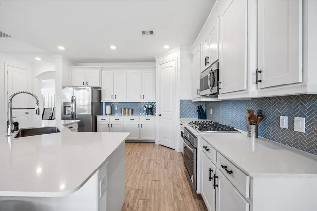 a kitchen with kitchen island a white counter top space a stove and cabinets