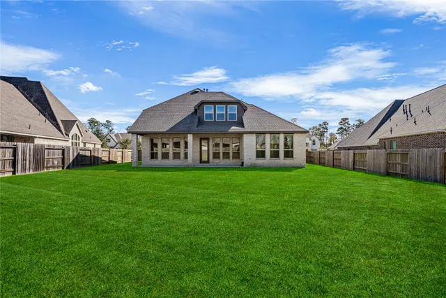 a view of a house next to a big yard with plants and large trees