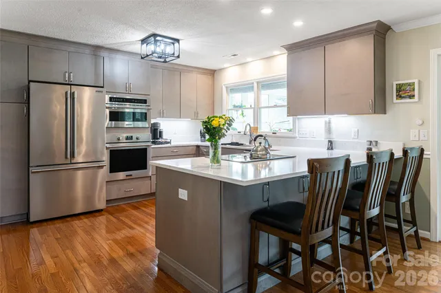 a kitchen with stainless steel appliances a dining table chairs microwave and sink