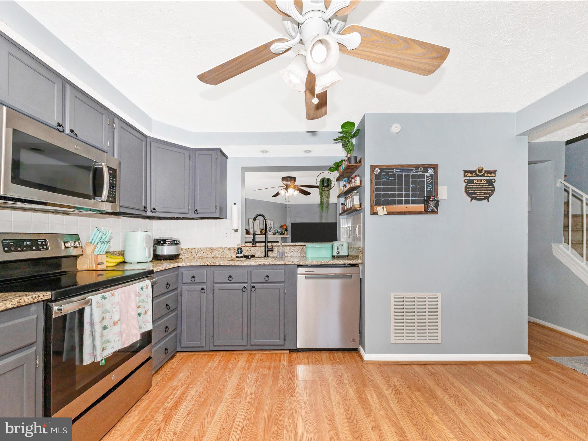 7283 Procopio Circle Columbia, MD 21046 - Photo 9 of 39 a kitchen with stainless steel appliances granite countertop a stove top oven a sink dishwasher and a microwave oven on the blue kitchen countertops with wooden floor