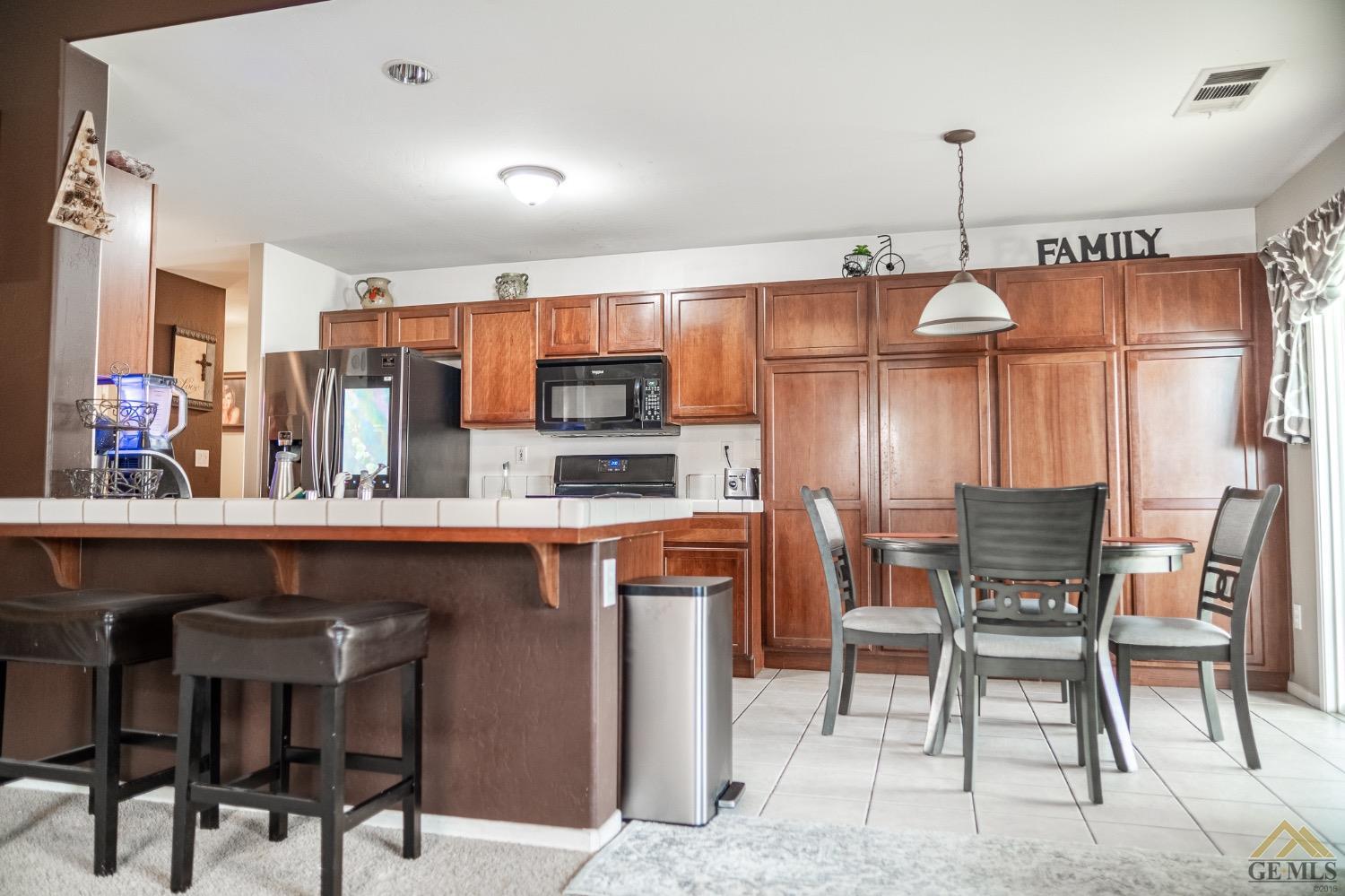Undisclosed Address Bakersfield, CA 93311 - Photo 11 of 26 a kitchen with stainless steel appliances kitchen island granite countertop a table chairs sink and cabinets