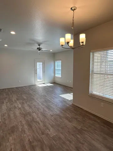 a view of a room with wooden floor chandelier and a window