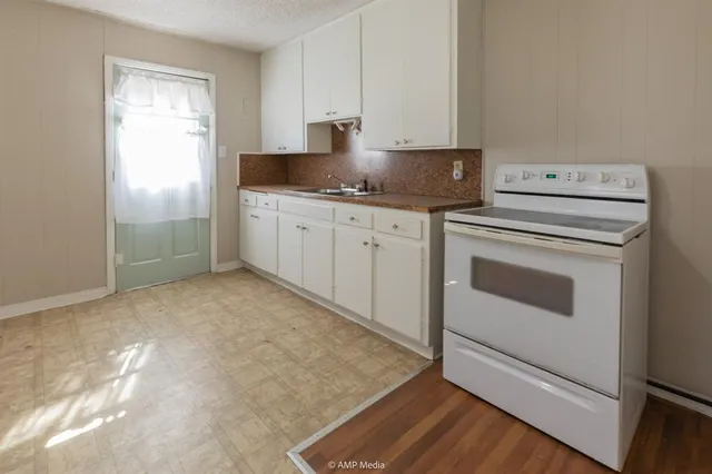 a kitchen with granite countertop white cabinets and white appliances