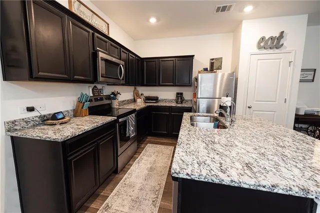 a kitchen with stainless steel appliances granite countertop wooden cabinets a stove and a sink