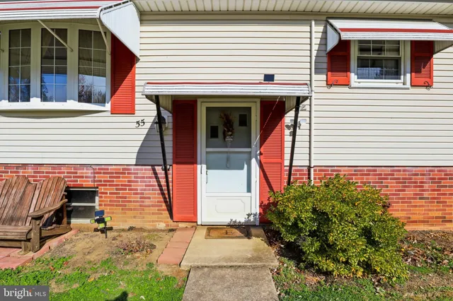 a view of a white house with large windows and a small yard