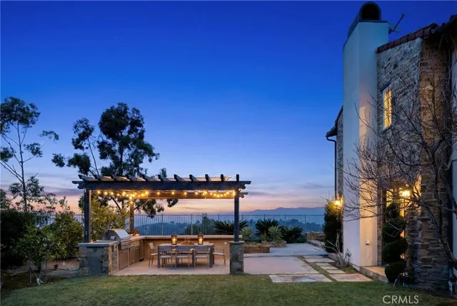 a view of a patio with a table and chairs under an umbrella with a barbeque