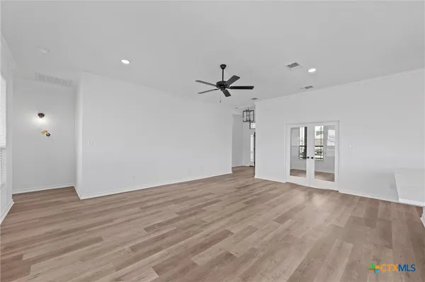 a view of empty room with wooden floor and ceiling fan