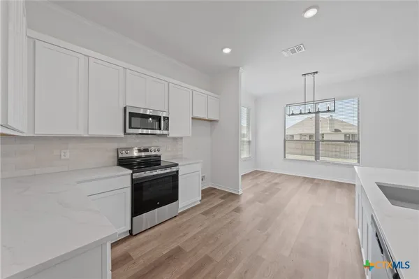 a kitchen with granite countertop white cabinets and stainless steel appliances