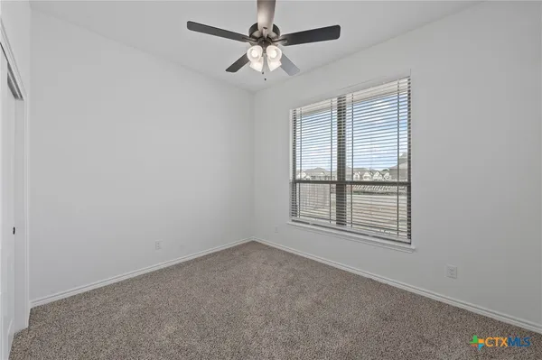 an empty room with a window and a fan