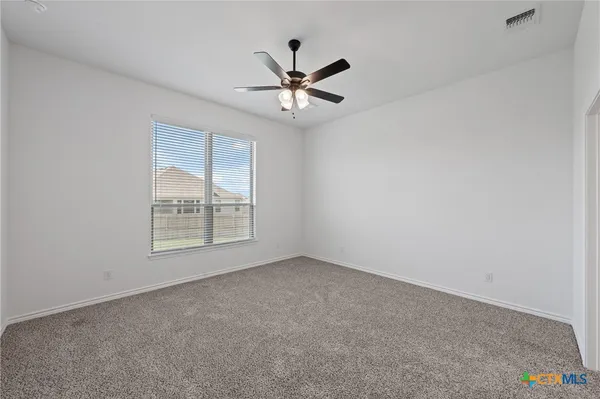 an empty room with a window and a ceiling fan